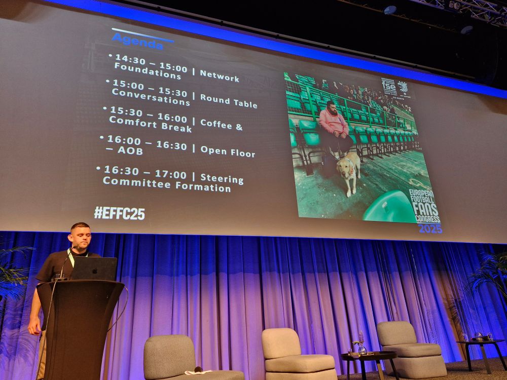 Image description: A big screen with a slide featuring Jon Attenborough and his beloved guide dog Sam, who recent passed away. There are details of the FSE agenda.