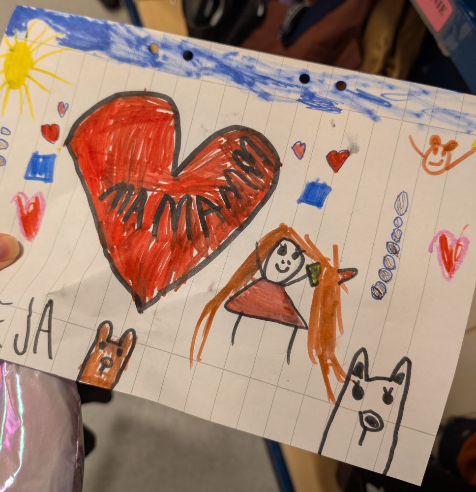 Bild på en teckning min femåriga dotter ritat. Ett stort rött hjärta där det står mamma. En streckgubbe med långt hår, ett par katter, en sol och blå himmel