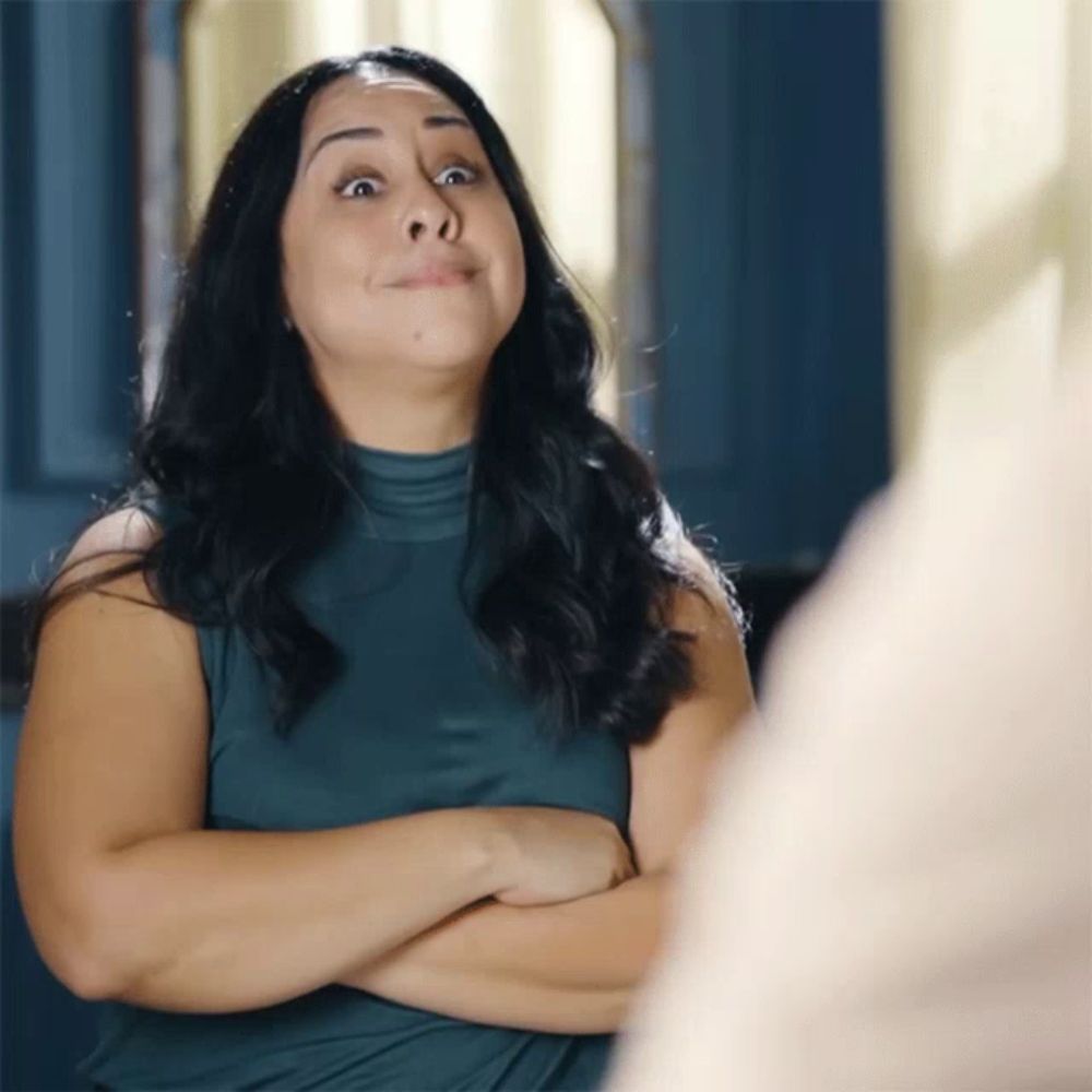 a woman with her arms crossed looking at herself in a mirror