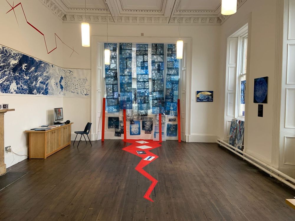 An art installation showing declining sea ice, at the end of a room with a red crack across the floor.