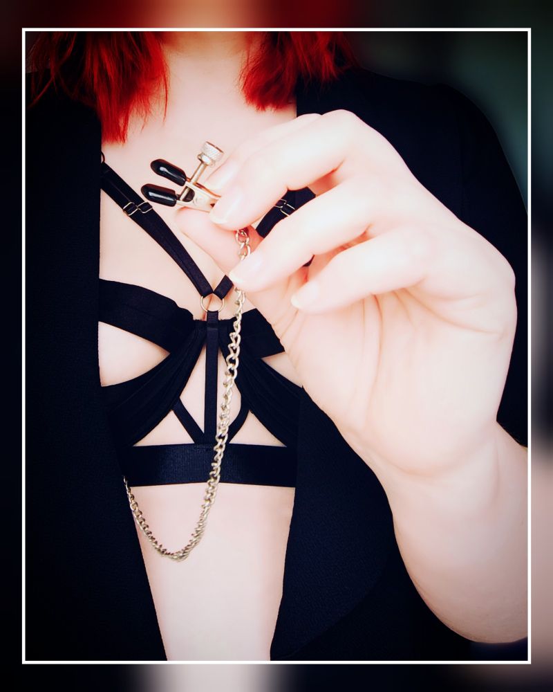 Farbiges Bild "Klammernliebe"
Darf ein BH, der nichts hält, eigentlich so heißen? Genau diese Frage muss man sich bei dem BH stellen, den ich auf diesem Bild trage. Er besteht aus minimal viel Stoff und Bändern, die nichts verdecken und somit freie Bahn für die Klammern schaffen. Eine davon ist an meiner Brustwarze befestigt, die zweite halte ich in die Kamera.
Von frivolen Spielzeug abgesehen ist natürlich wieder alles züchtig bedeckt.