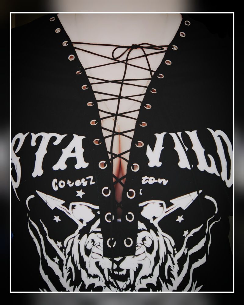 Schwarz-weiß-hautfarbenes Bild "zugeschnürt"
Ich trage ein schwarzes Shirt mit der Aufschrift STAY WILD und einen Tiger drunter. Der Ausschnitt ist ein tiefes V mit Nieten, durch die überkreuzte Schnüre gezogen sind.