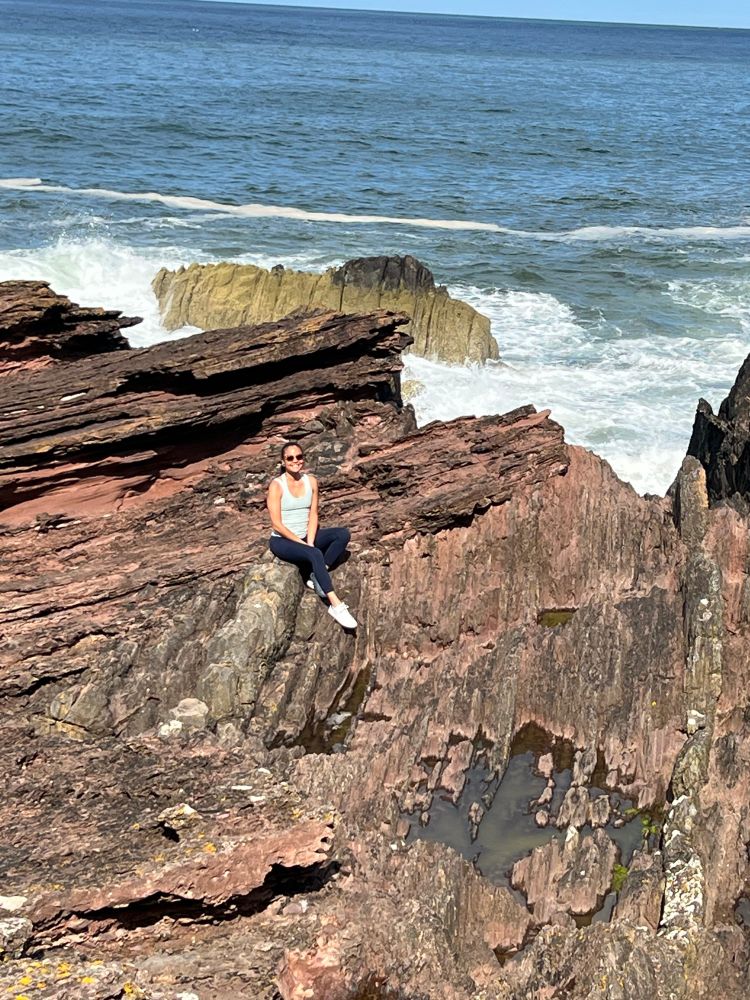 Edith sitting on rocks at Siccar Point, Scotland! 