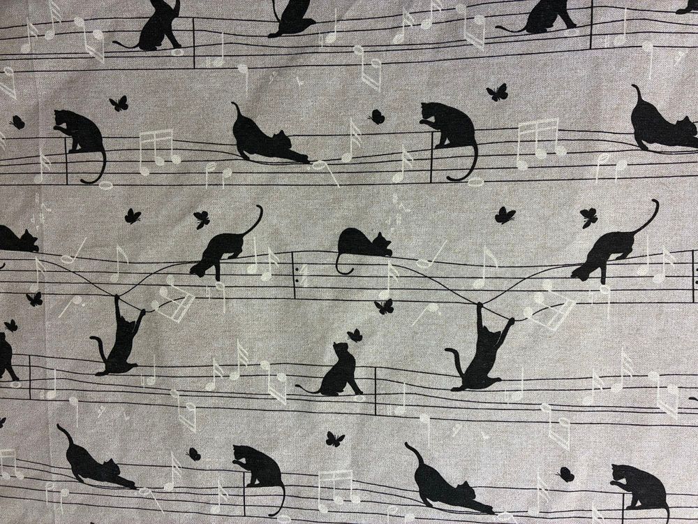 Beiger Stoff mit schwarzen Notenlinien, auf denen schwarze Katzen herumturnen