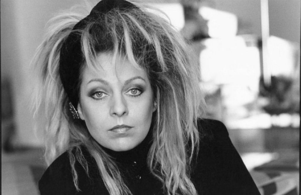 Eine hübsche Frau, die konzentriert in die Kamera schaut, deren Haare wild um den Kopf liegen