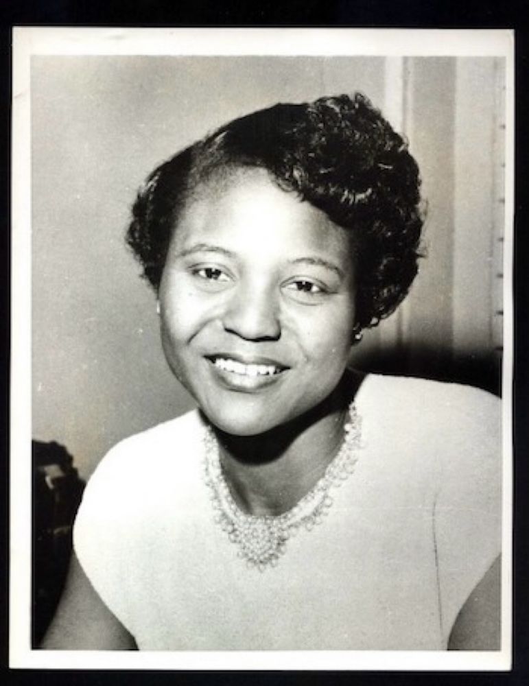 Eine junge Frau im weißen Kleid, mit Kette, die freundliche, die Kamera lächelt