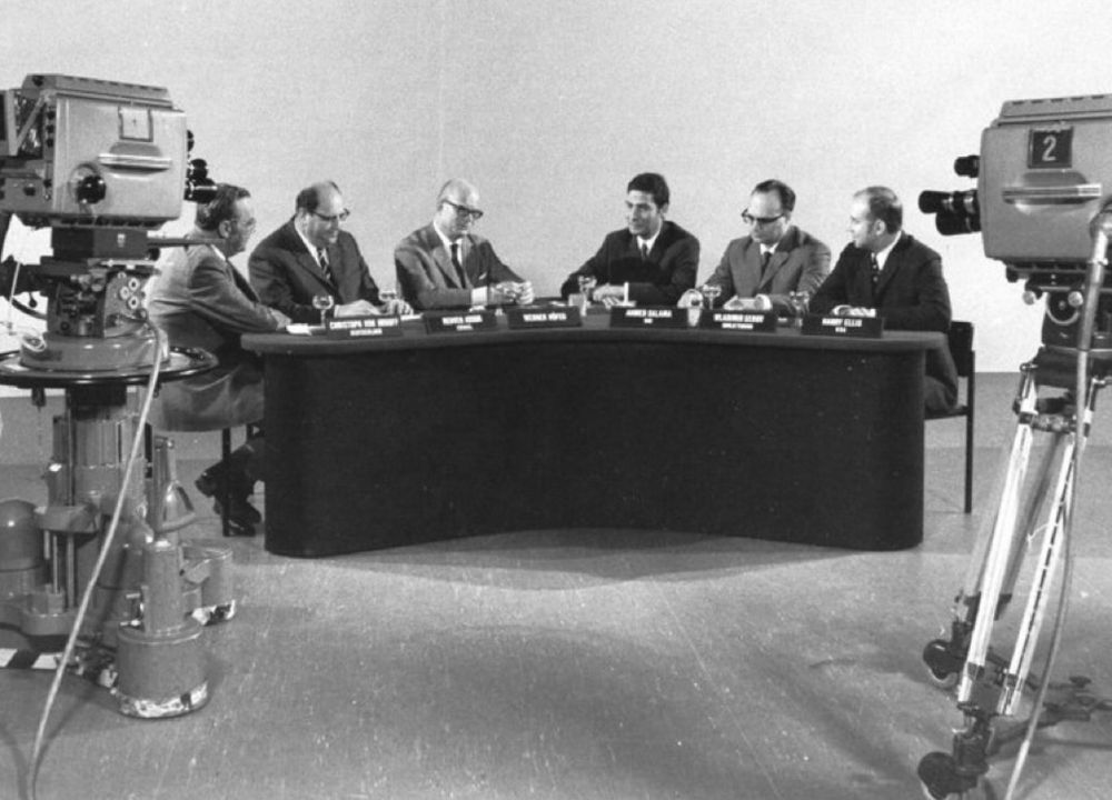Das Foto einer der ersten Aufzeichnungen alle saßen an einem leicht gebogenen Tisch, in der Mitte der Moderator