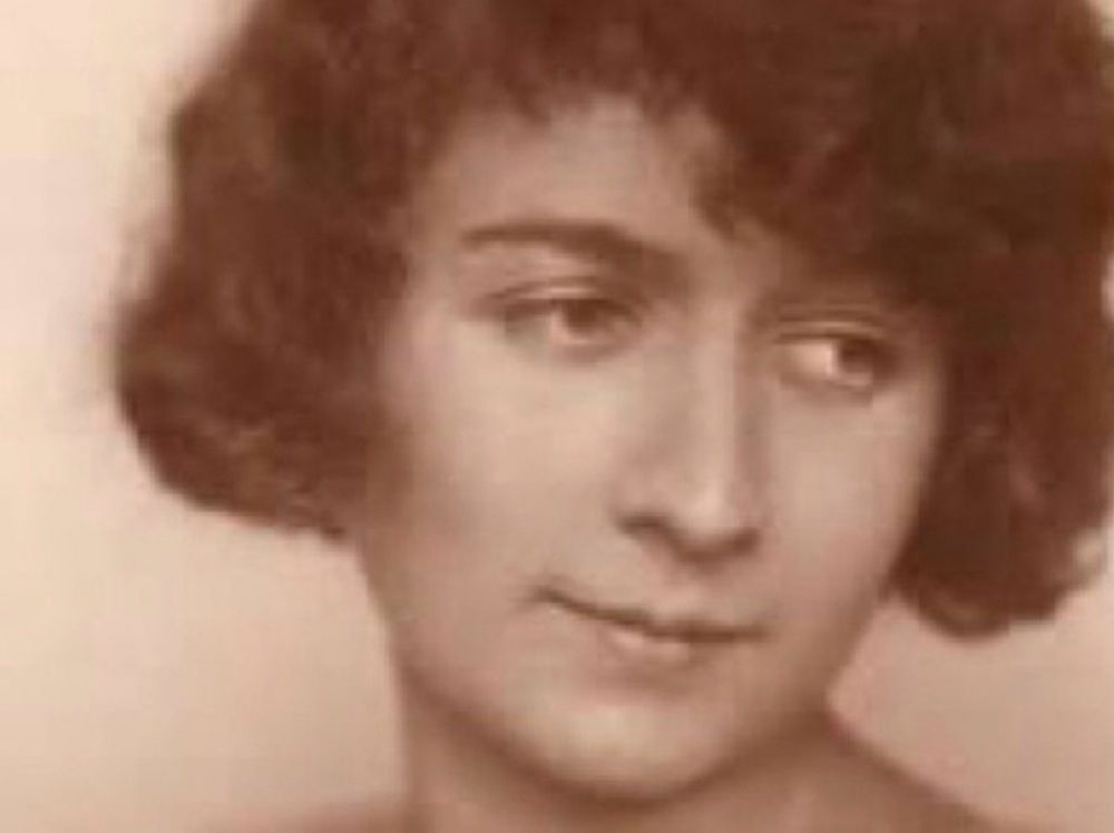 Ein Foto von ihr als junger Frau, sie hat ein weiches Gesicht, halb lange, lockige Haare und schaut zur Seite