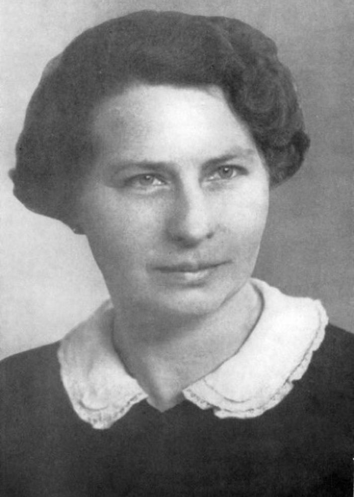 Ein junge Frau, die ein Oberteil mit einem weißen Kragen trägt, schaut entspannt in die Kamera, hat kurze Haare