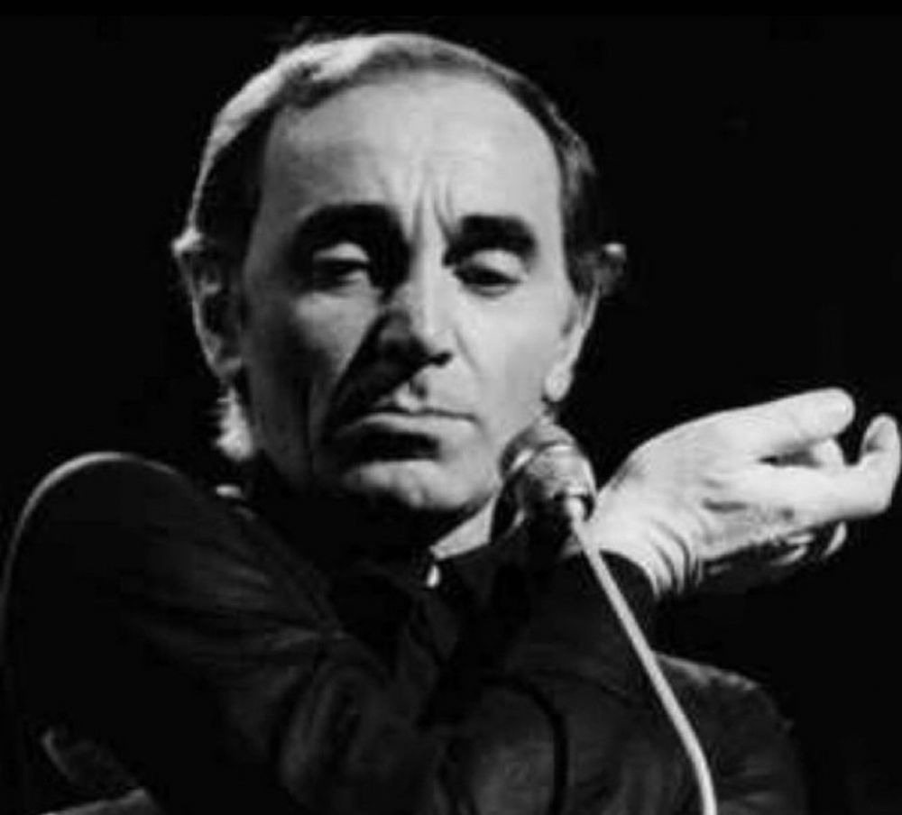 Ein Foto von dem Sänger. Er steht am Mikrofon, schaut nach unten.