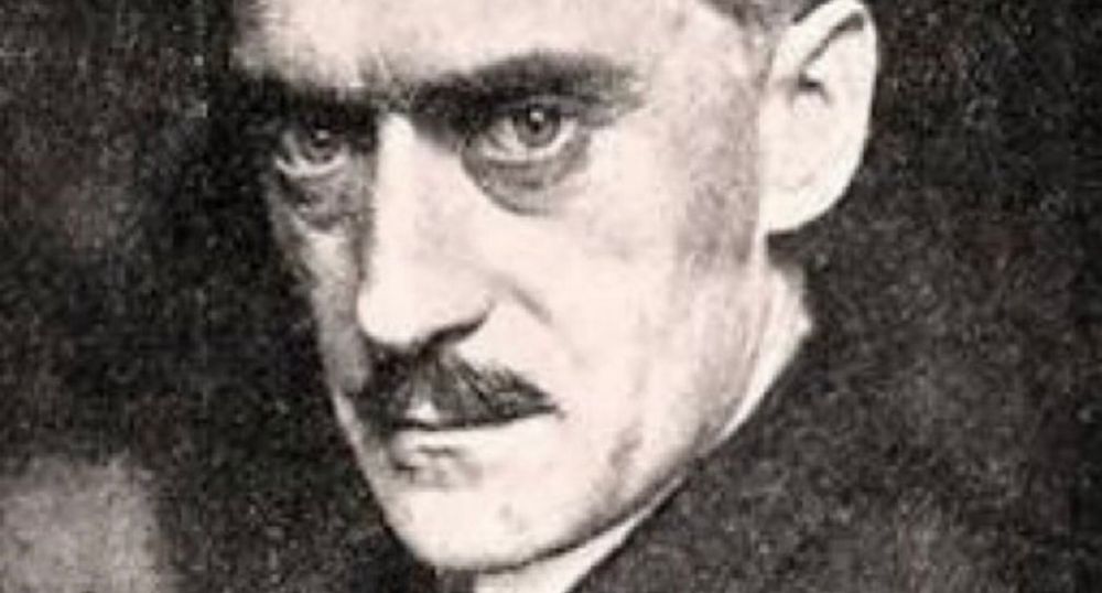 Man sieht nur sein Gesicht, mit dem kleinen Oberlippenbart, den ernsten Augen, die den Fotograf betrachten