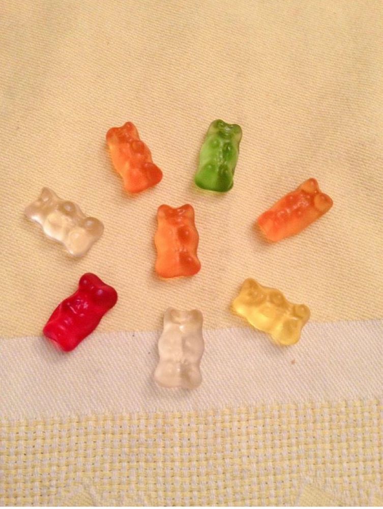 Auf einer Tischdecke liegen mehrere kleine Gummibären in unterschiedlichen Farben 