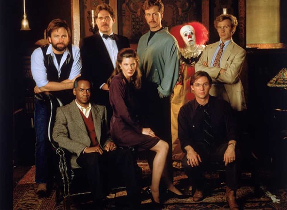 Cast of It with Pennywise looking confused at the back