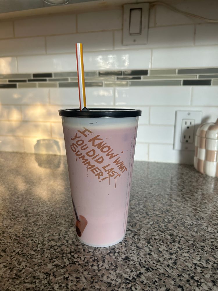 Photo of a promotion cup from Cineplex that is white with the text I Know What You Did Last Summer turning red with cold liquid inside.