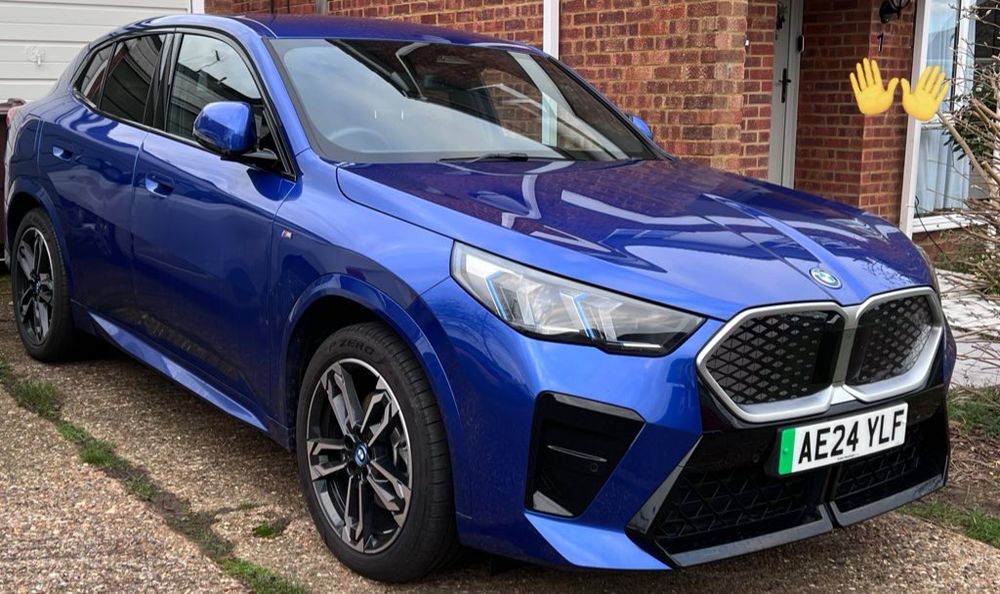 A blue BMW IX2 electric car in a driveway