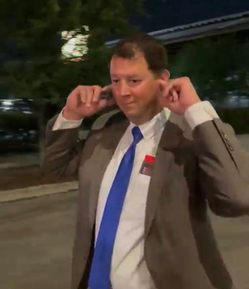 A democrat plugging his ear at the jeers of pro-palestine protesters and walking by