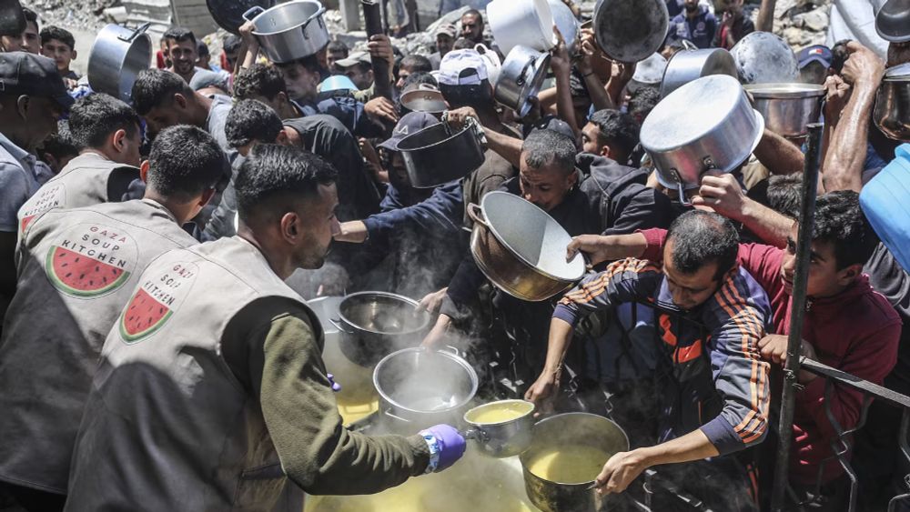 Des Palestiniens déplacés attendent de recevoir des repas chauds distribués par des associations, le 6 mai 2025 à Beit Lahia, dans la bande de Gaza