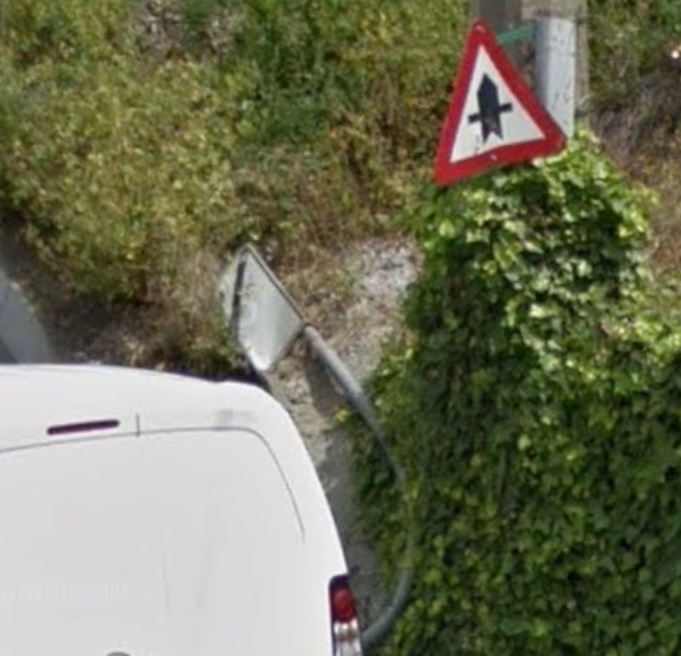 capture street view, 2017, même emplacement. Le panneau fin de zone 30 est à terre, le poteau en béton se fait grignotter par du lierre qui arrive juste sous le panneau triangulaire de fin carrefour prioritaire.