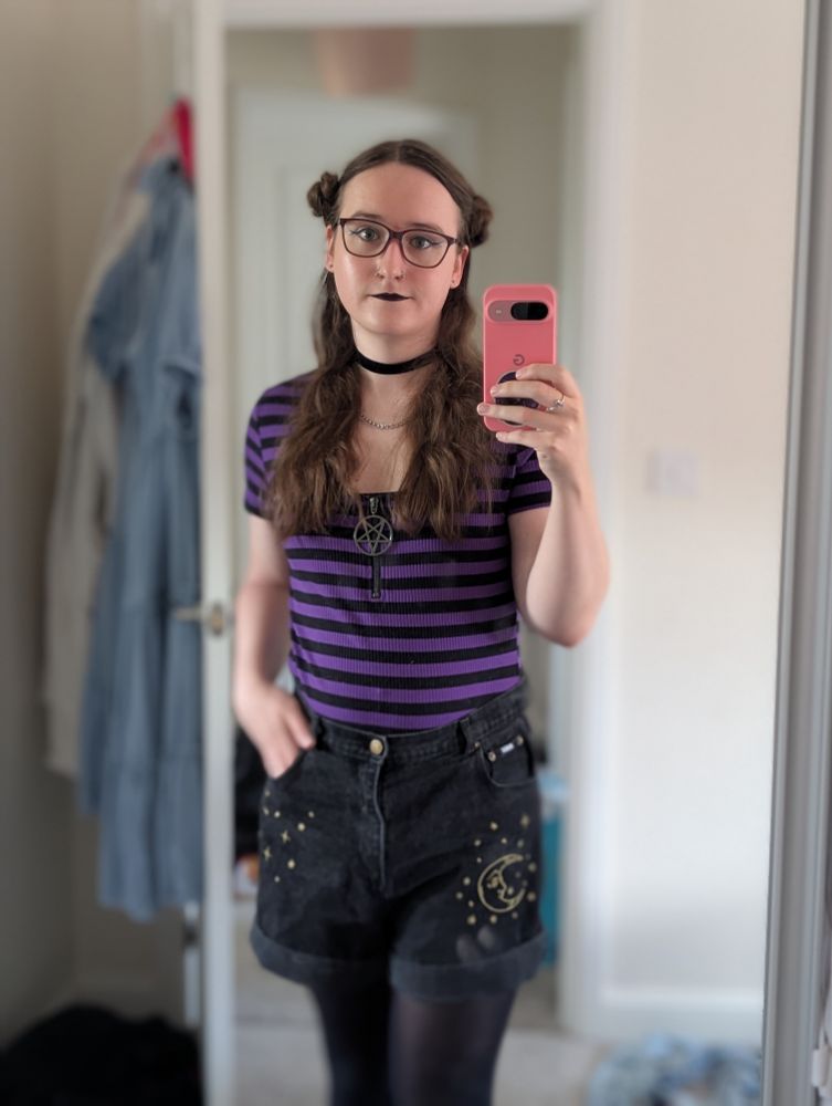 A cute woman stands and takes a photo of herself in the mirror