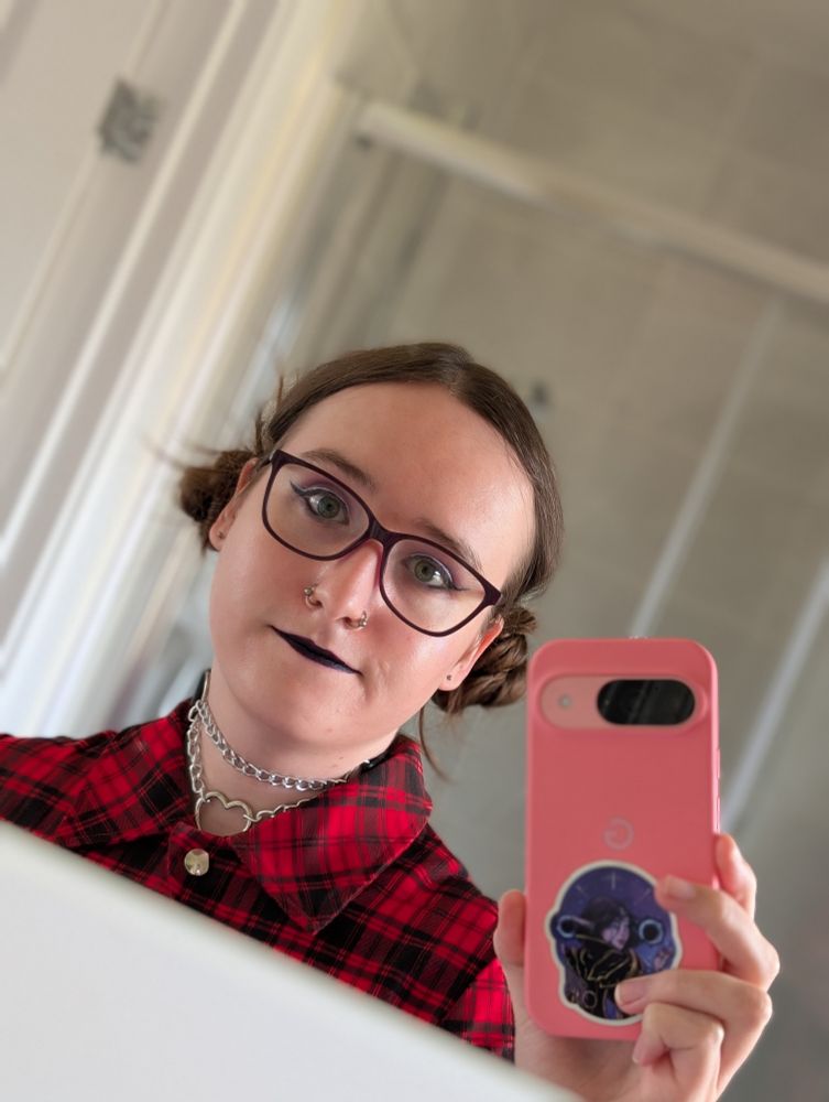 A cute woman takes a photo of herself in the mirror holding a pink phone
