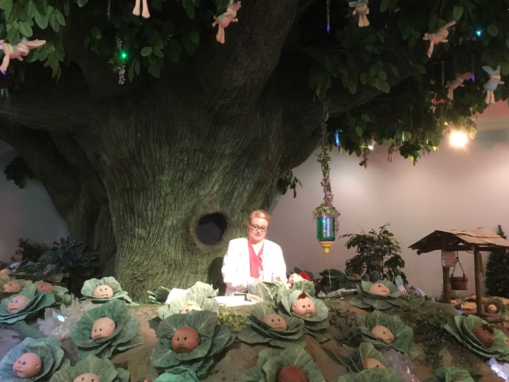 a nurse standing under a large tree "delivers" a Cabbage Patch Doll baby at the Babyland General Hospital in Cleveland, Georgia