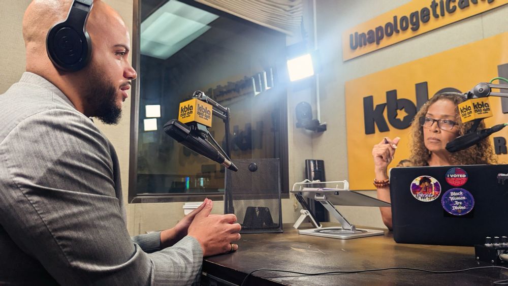 Photo of Assemblymember Isaac Bryan and Dominique DiPrima sitting in a radio recording booth. 