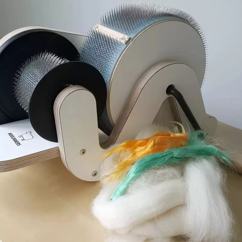 Natural cream Shetland fibre and mulberry silk in yellow and turquoise along side a Woolmakers Hero drumcarder.