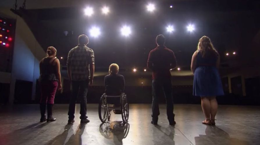 A shot from behind of Aylin, Blake, Ali, Michae, and Lily Mae on The Glee Project, with the five of them silhouetted by the stage lights.