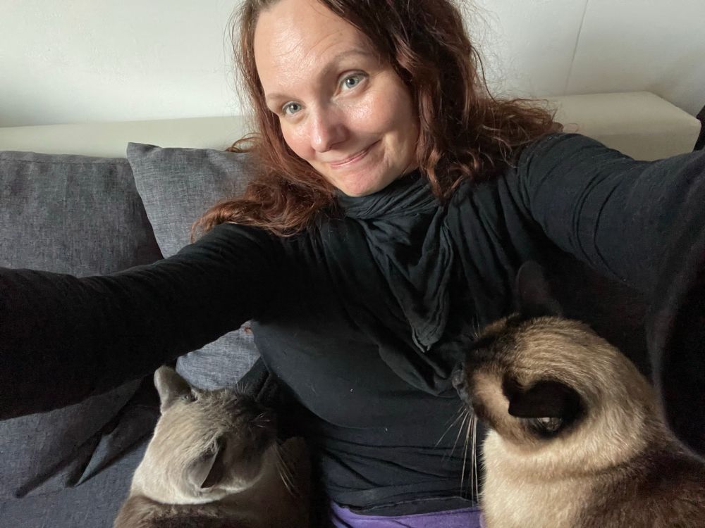 Schwarzwaldmadl mit zwei Siam-Katzen kuschelnd