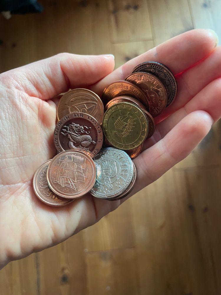A hand full of LARP coins on copper, silver and gold