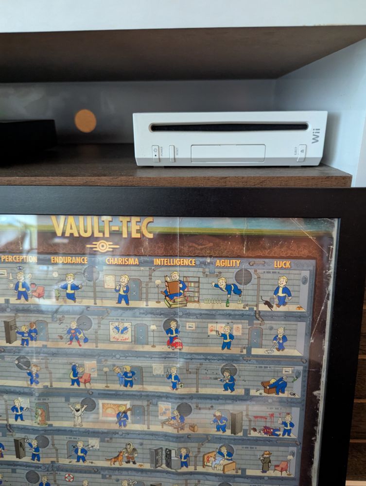 Picture of a Wii, next to a framed poster of the Fallout Vault-Tech technology tree