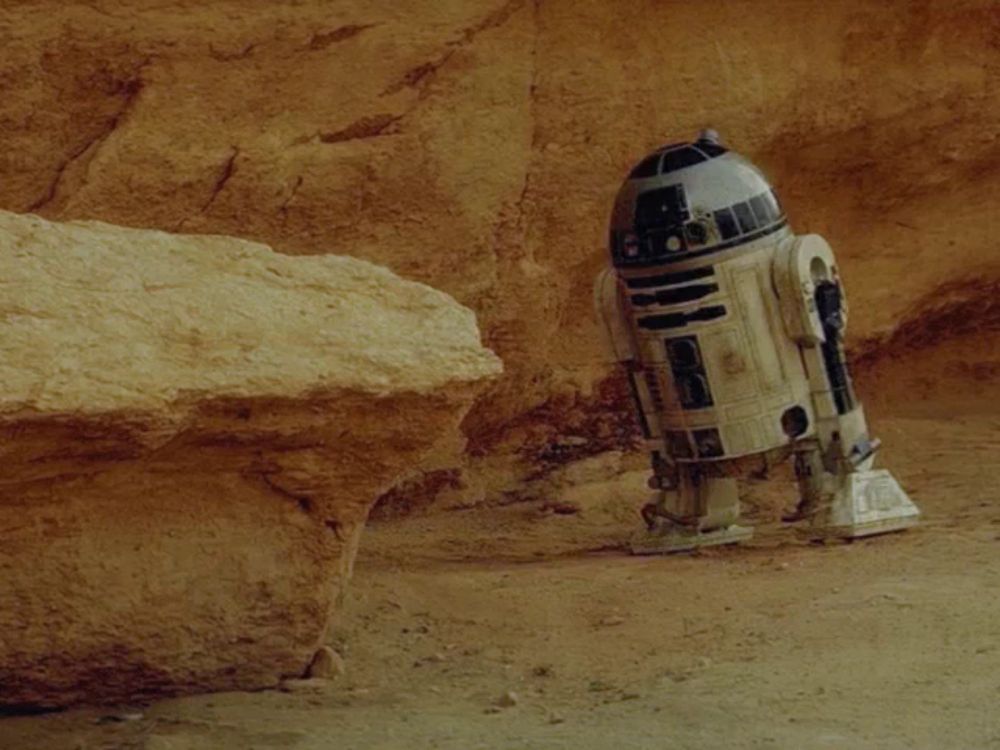 a r2d2 robot is laying in the dirt next to a rock