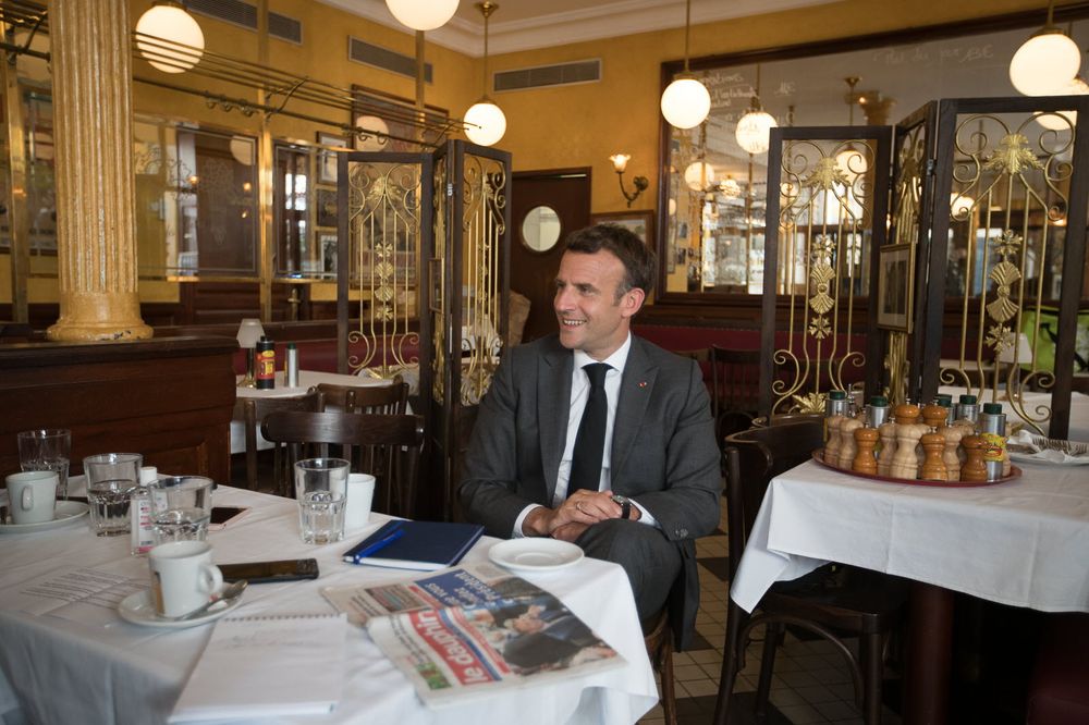 Emmanuel Macron hilare à une table de restaurant. Hors-champ, des gens qui n'avaient pas envie de l'avoir à leur table.