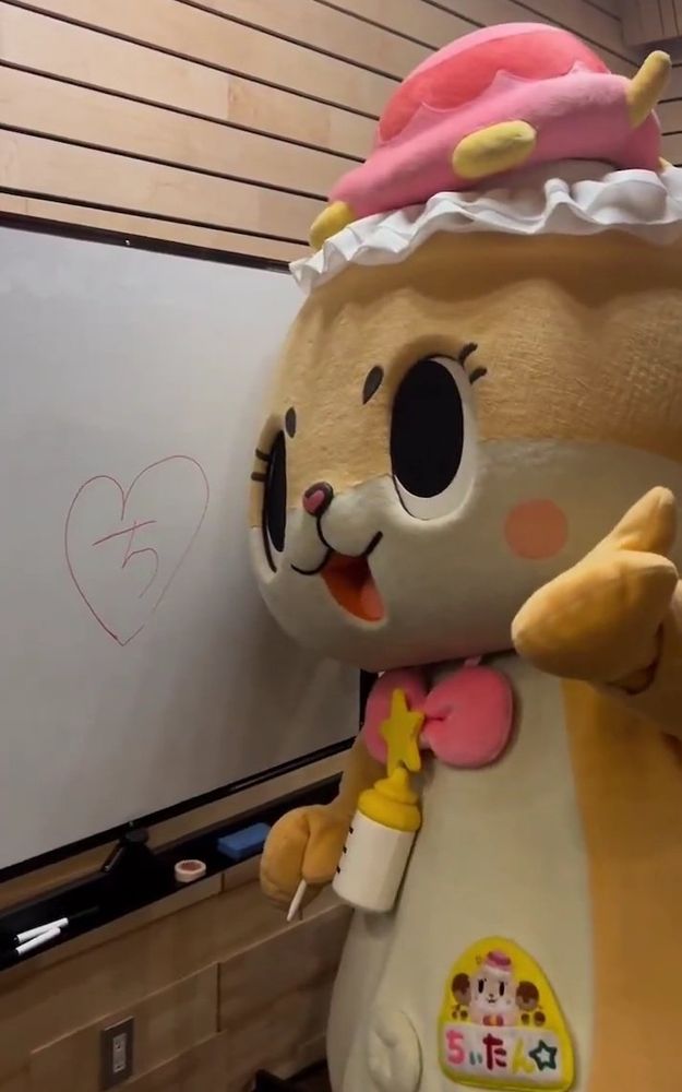 Fairy baby otter chiitan (ちいたん) standing in front of a whiteboard with a drawn chi hiragana symboled inside a heart.