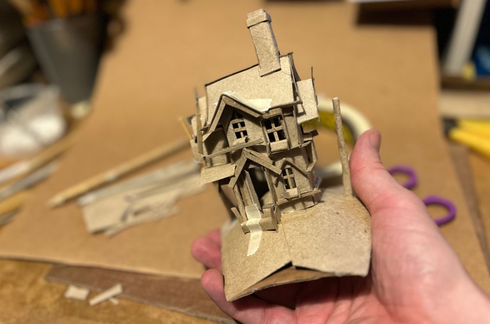 A model of a Christmas Cottage made from recycled cardboard tubes, small enough to fit in my hand. 