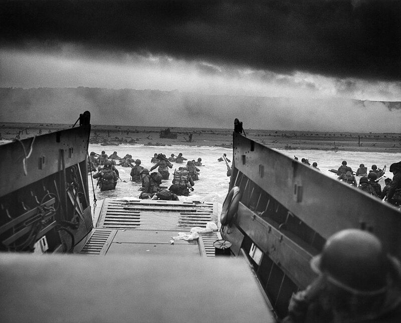 Black and white photo of soldiers leaving a landing craft on the Normandy beaches