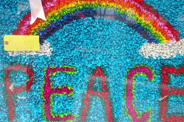 The word "PEACE" and a rainbow made from thousands of origami cranes.