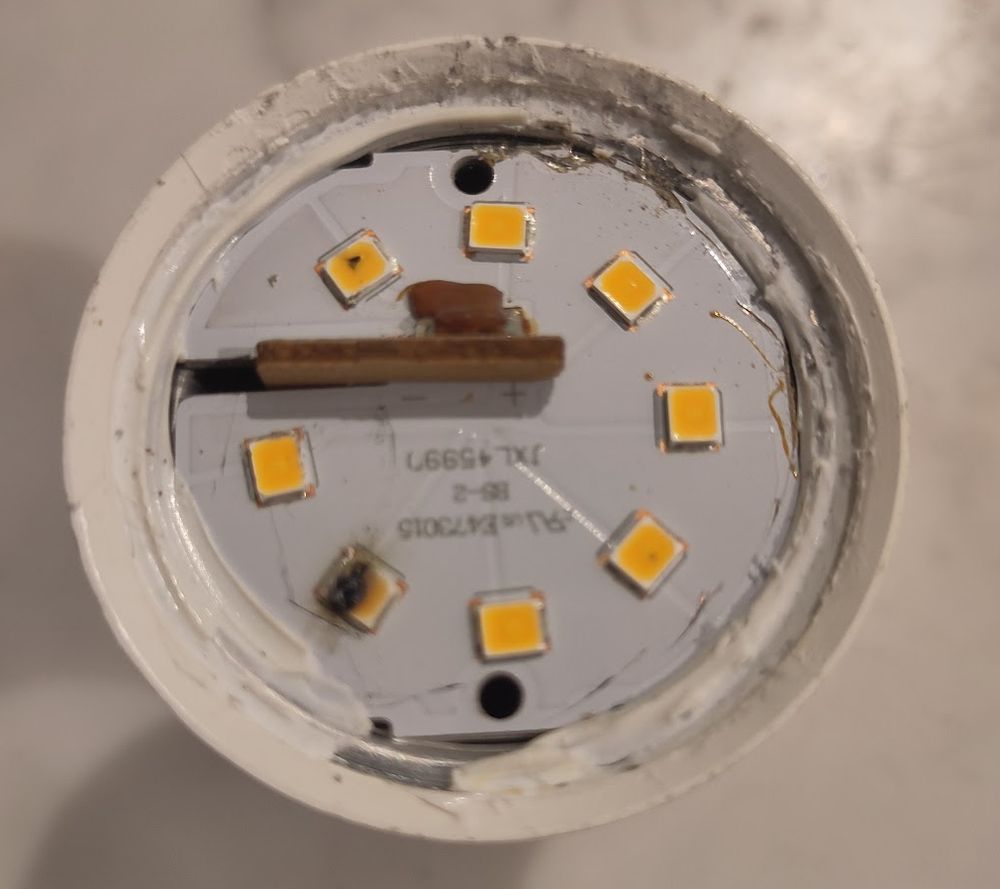 If you take the bulb part off an LED light bulb you see this - a ring of yellow squares - the actual LEDs - on a grey background. One of them has a black smear across it where its failed.