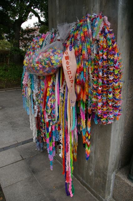 chains of origami birds on a concrete wall, many colours