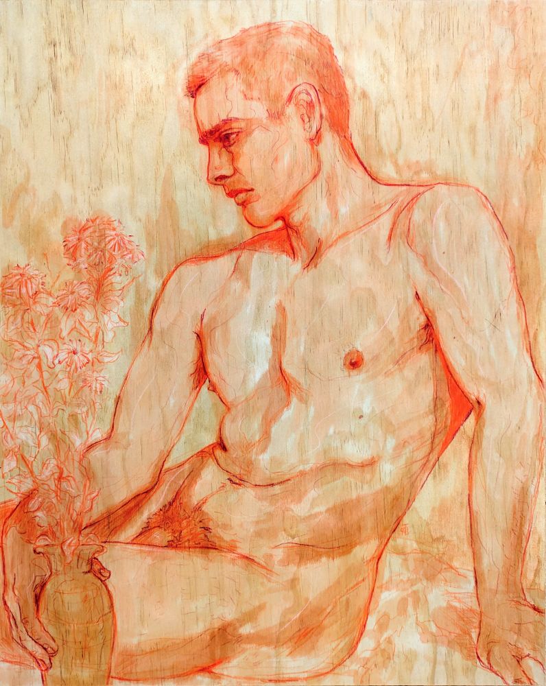 Man sat down, holding a vase of tall flowers. He has a forlorn expression. 