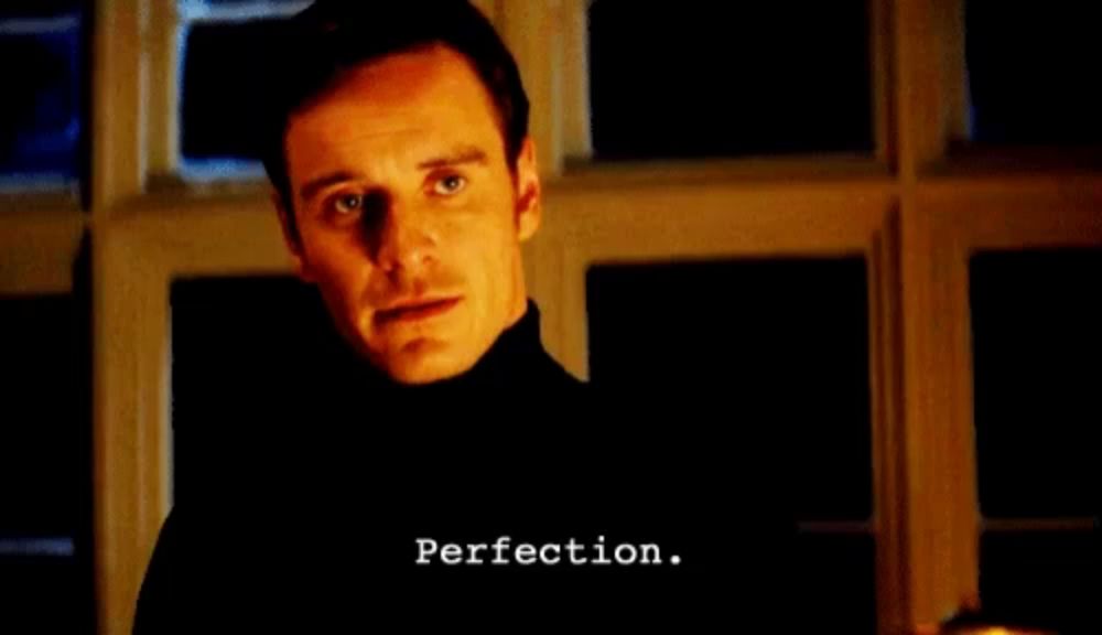 a man in a black turtleneck is standing in front of a window with perfection written on the bottom of his face .