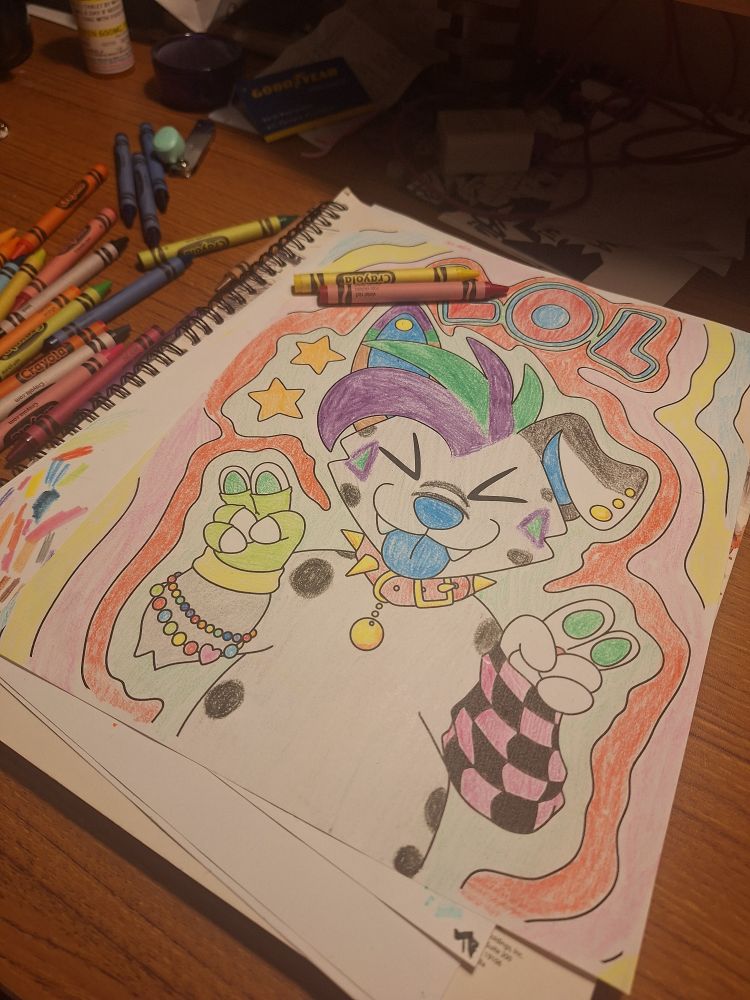 A page of my coming-soon coloring book. It has been colored in with Crayola crayons. A few of the crayons are scattered around on the page and the desk.