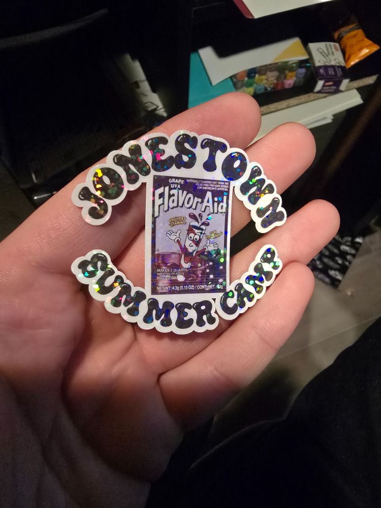 Shiny sticker of a packet of grape flavor aid that says Jonestown Summer Camp