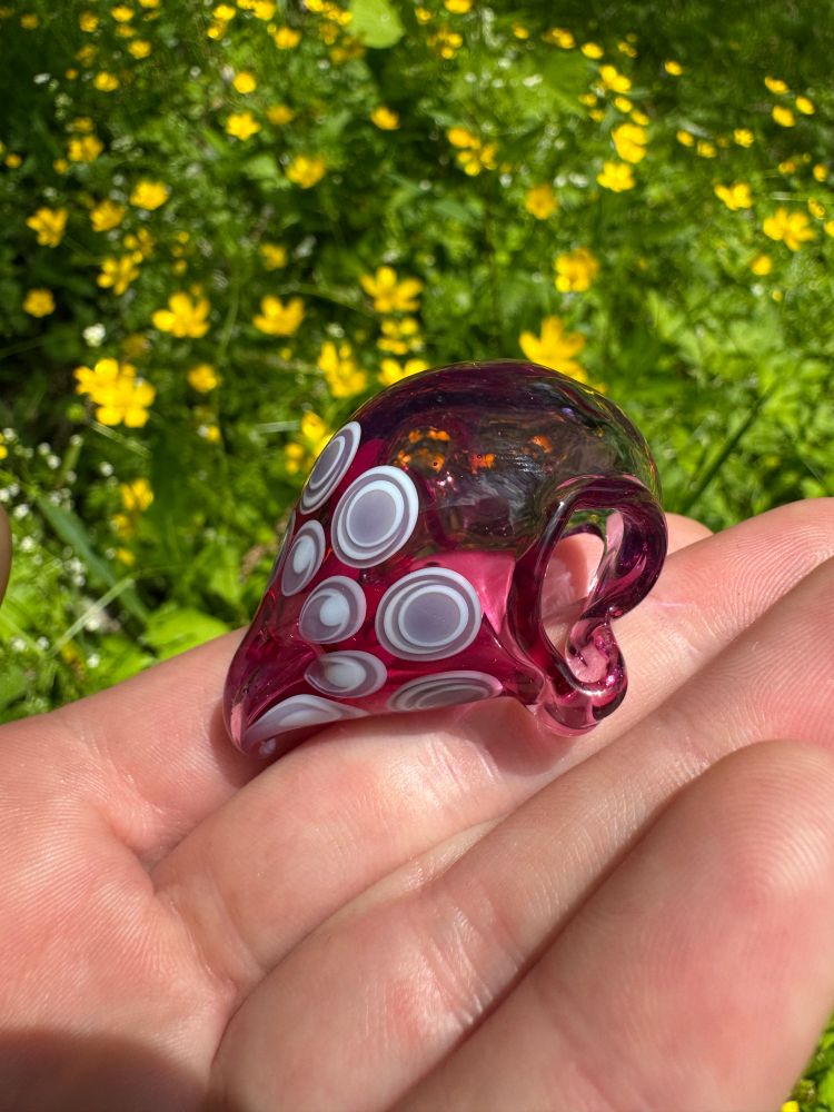 A hollow bird skull made with a fade of purples and pinks. The beak is adorned with a doctors pattern in white and light purple. Can be worn by looping a necklace through the eyes. Sitting on my hand 