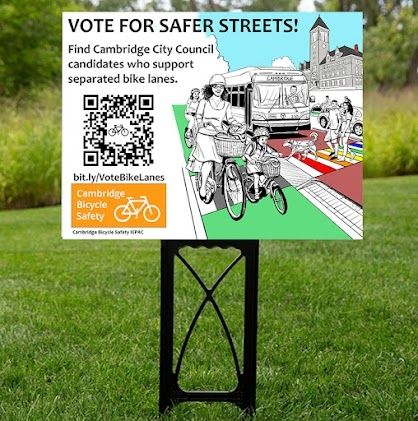 A colorful sign on a green lawn. The left side of the sign reads, "Vote for Safer Streets! Find Cambridge City Council candidates who support separated bike lanes. [QR code]
Bit.ly/VoteBikeLanes
Cambridge Bicycle Safety IEPAC" 
On the right side of the is a cartoon depicting a woman and child bicycling in a green bike lane, while two people and a dog walk in a rainbow crosswalk, and a MBTA transit bus and Cambridge City Hall are in the background.