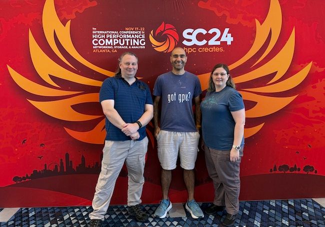 RCC's Ashley Wright, Jake Carroll, and Sarah Walters in front of a SC24 banner.