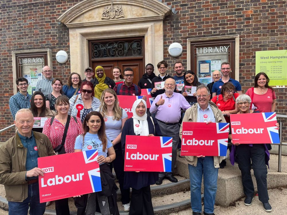 Photo of Labour campaigners outside West Hampstead library holding posters and signs 