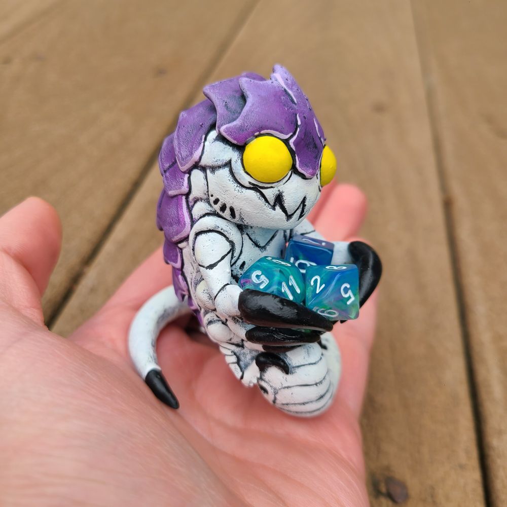 A painted figure of a tyranid from warhammer 40k in someone's hand.  