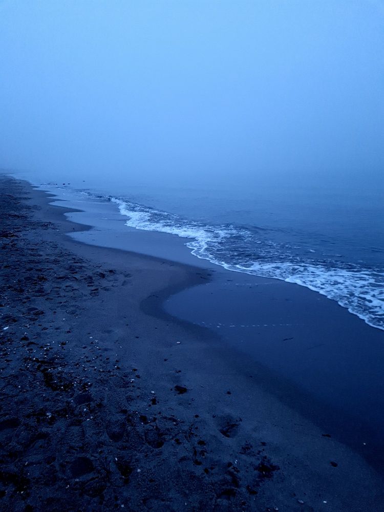 Meer und Strand in der Abenddämmerung an einem neblig- kalten Wintertag.