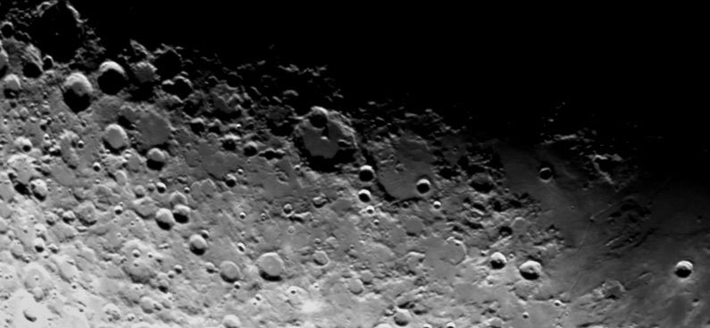 Black and white lunar closeup with bright highlight X on top left and V on top right. 